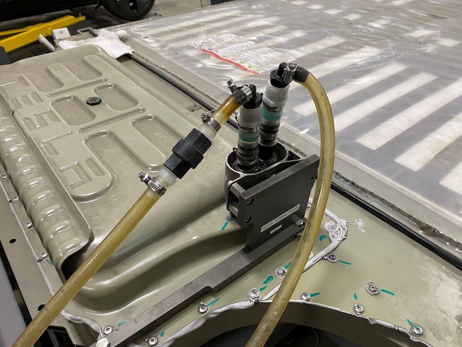 Batterijpakket met zelfsluitende snelkoppelingen van een Tesla. Links de 'drain hose' voor aftappen en rechts de 'fill hose' voor bijvullen.